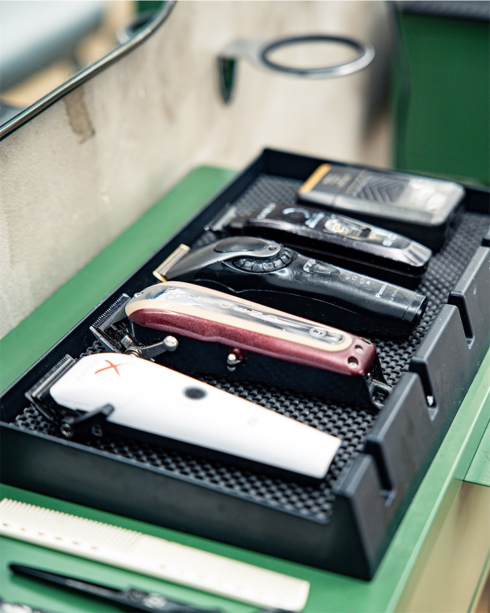 Tondeuses et outils sur le plan de travail vert du salon Hair Lab